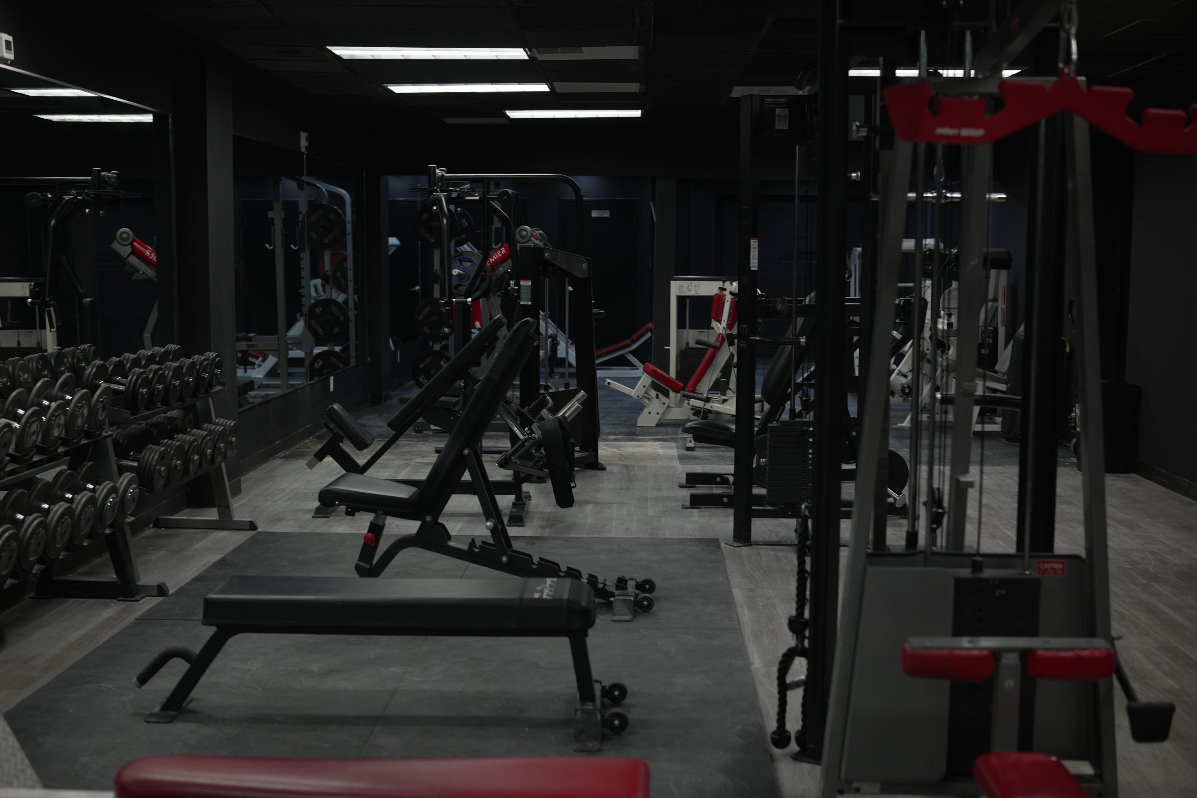 Hadeed's training floor: adjustable benches, cable towers and dumbbell racks under black walls
